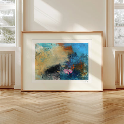 Framed abstract painting on a wall with large windows and wooden floor