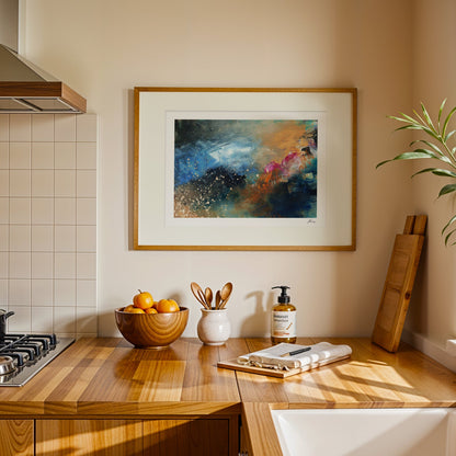 Kitchen counter with a bowl of fruit, utensils, and a bottle of soap, with a colorful abstract painting on the wall.