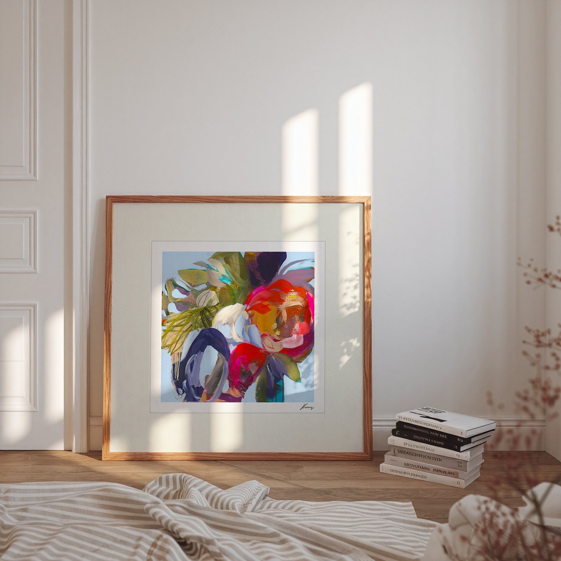Framed abstract artwork on a wall with books and decor items below