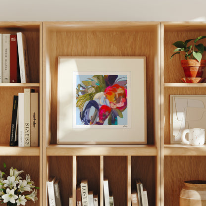 Framed abstract art piece on a wooden bookshelf with books and decor items.