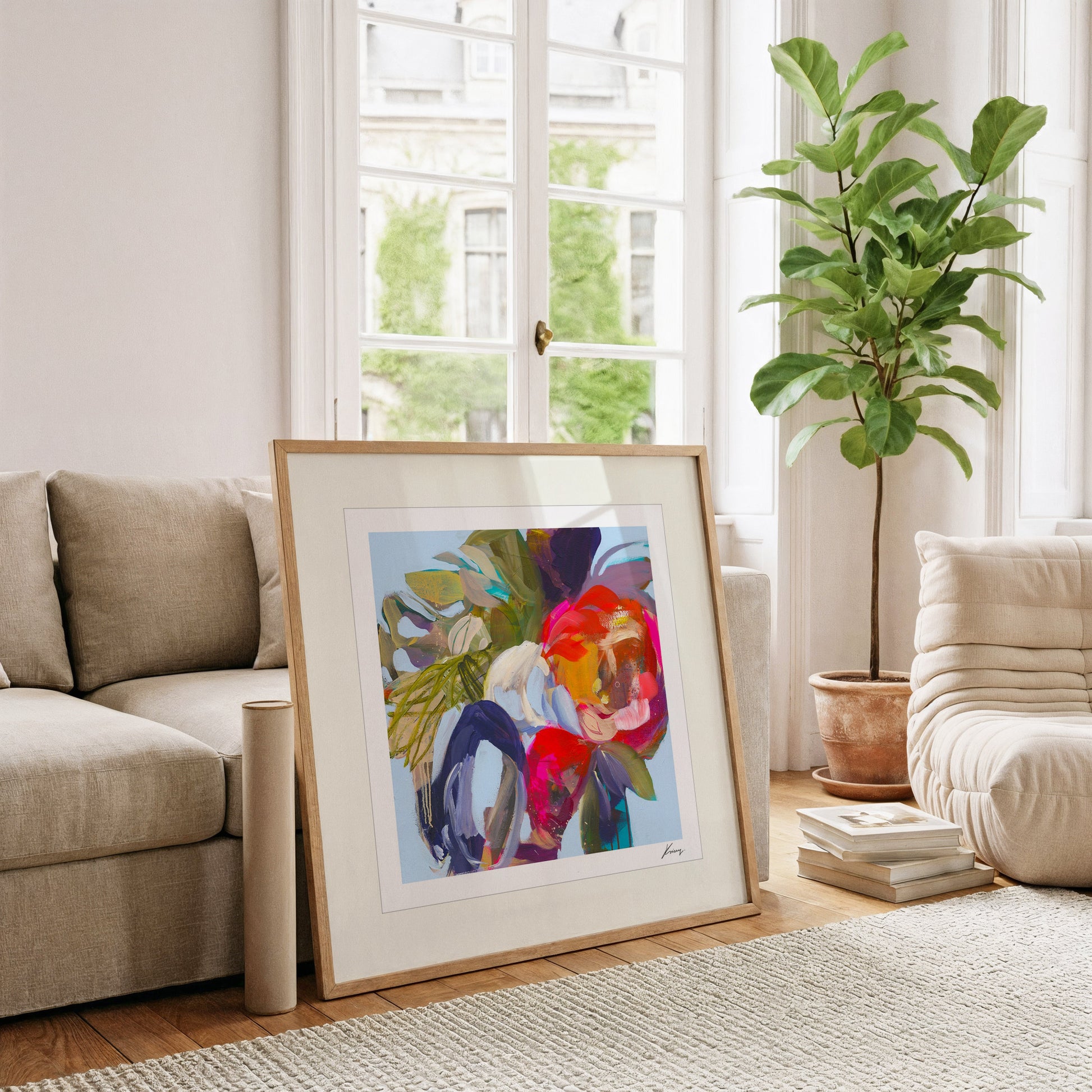 Framed abstract art in a living room with a couch, plant, and books.
