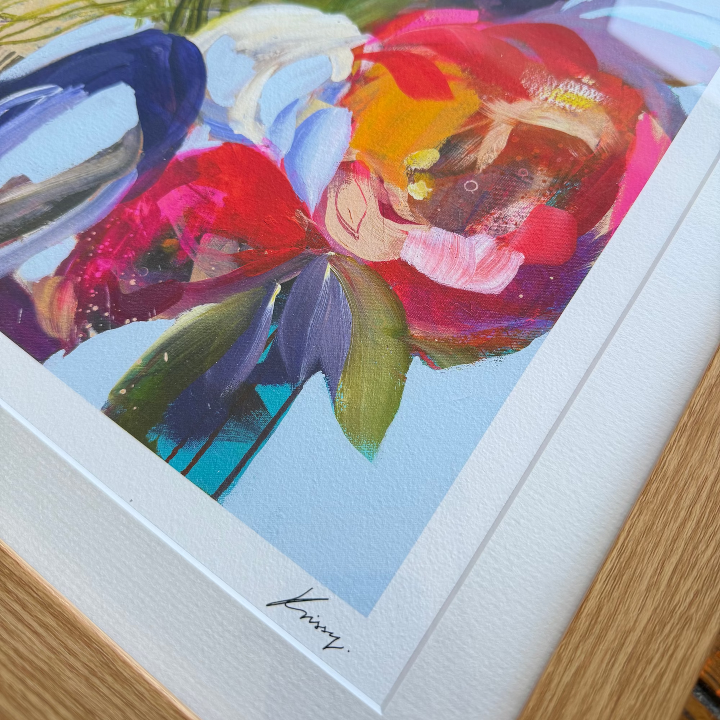 Framed abstract artwork with vibrant colors on a wooden surface