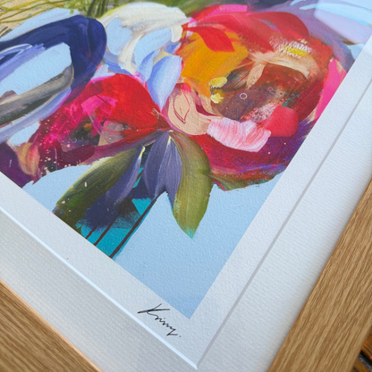 Framed abstract artwork with vibrant colors on a wooden surface