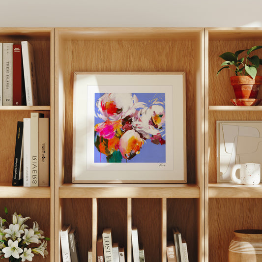 Framed floral artwork on a wooden bookshelf with books and decor items.