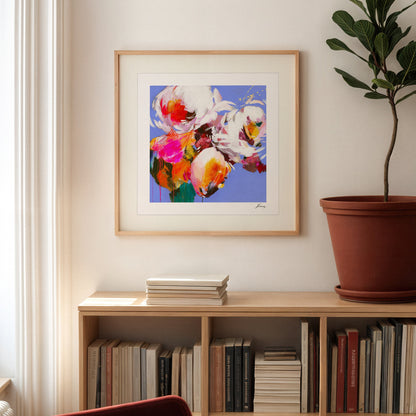 Framed abstract artwork on a wall above a bookshelf with books and a plant.