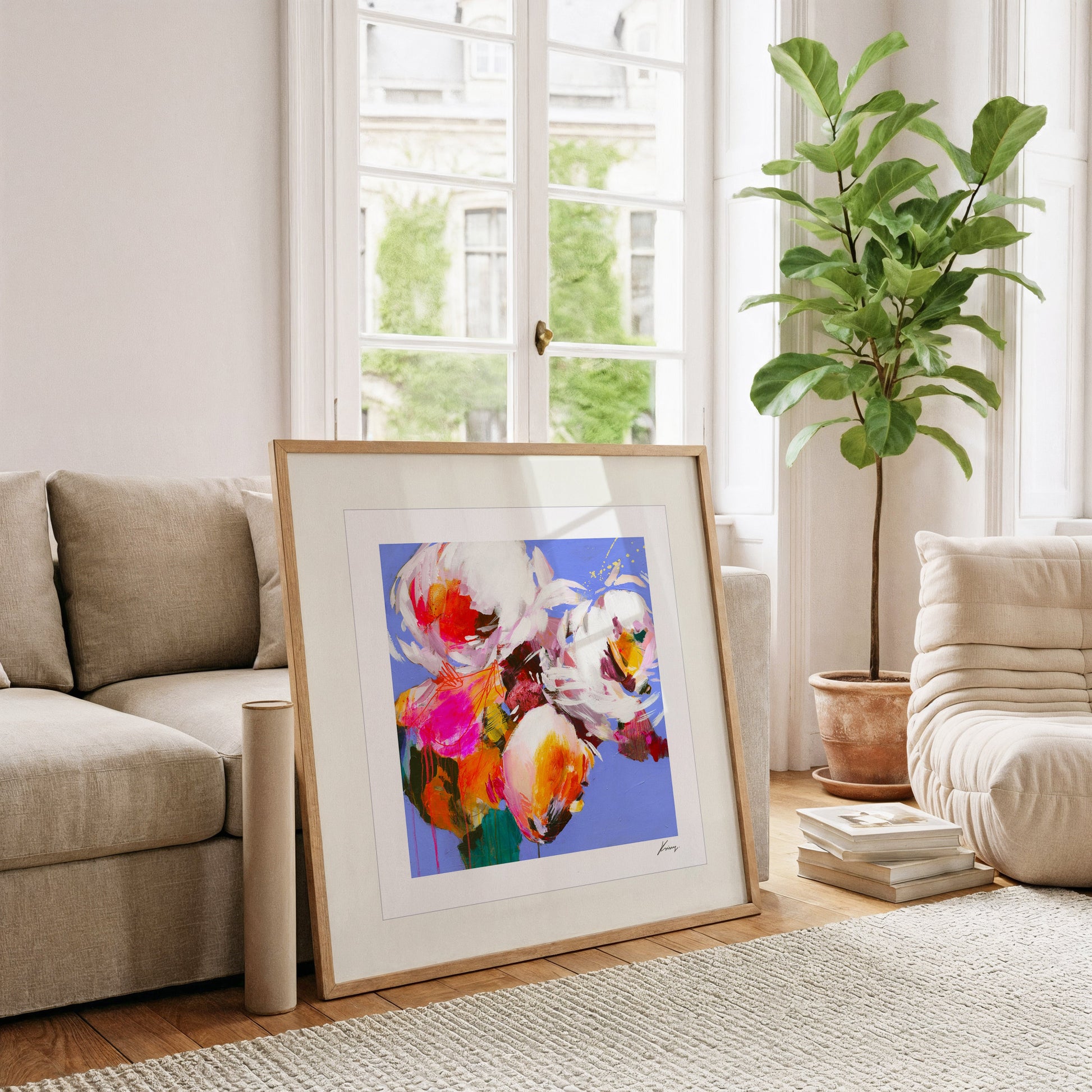 Framed abstract art piece on a coffee table in a living room with a couch and plant.