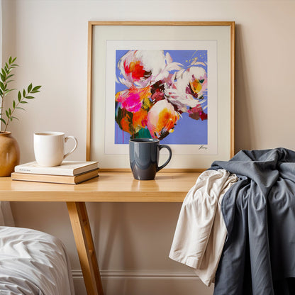 Framed colorful abstract art on a wooden side table with books and mugs.