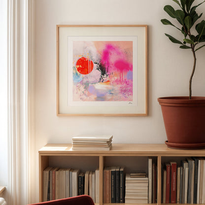 Framed abstract art on a wall above a bookshelf with books and a plant.