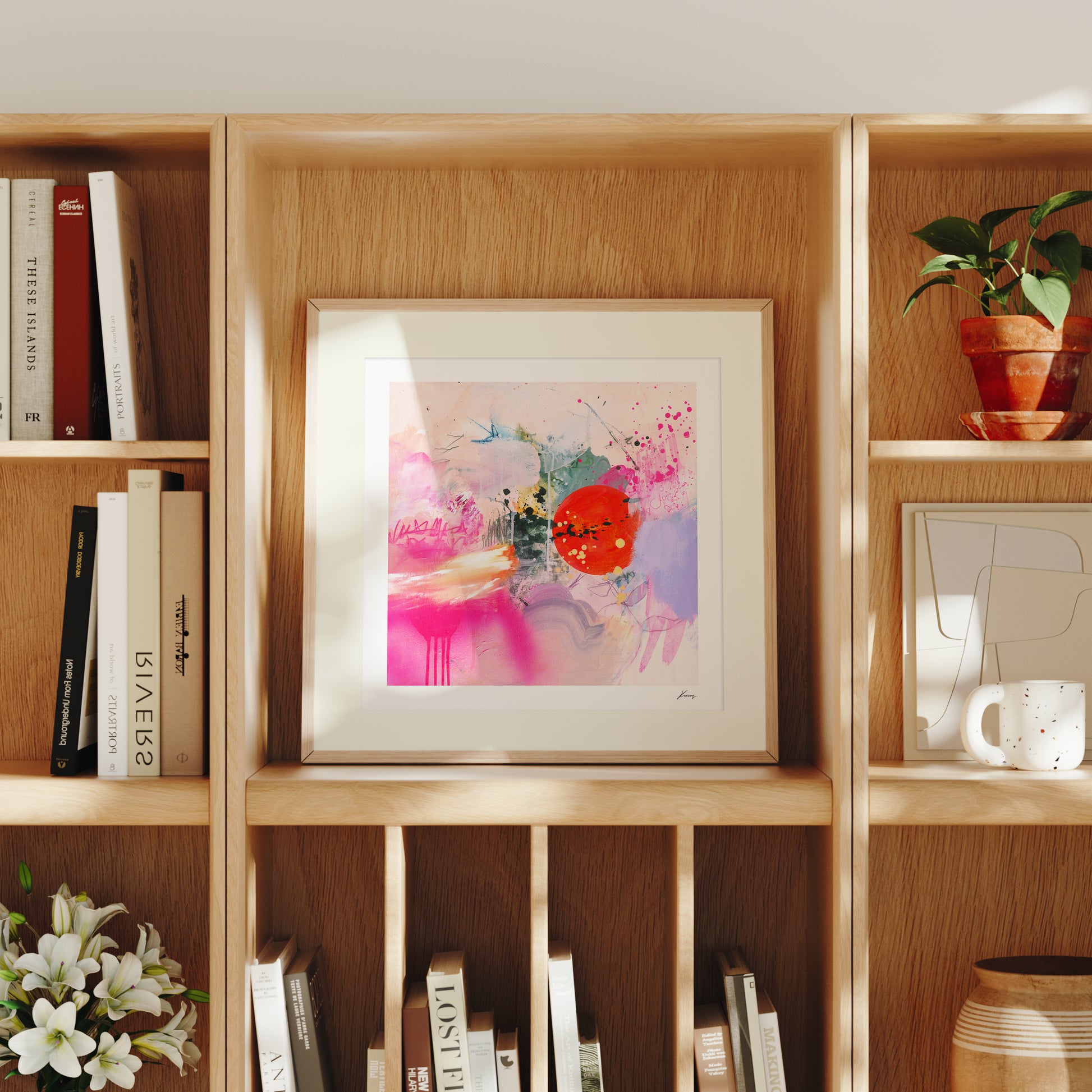 Framed abstract art on a wooden bookshelf with books and decorative items.