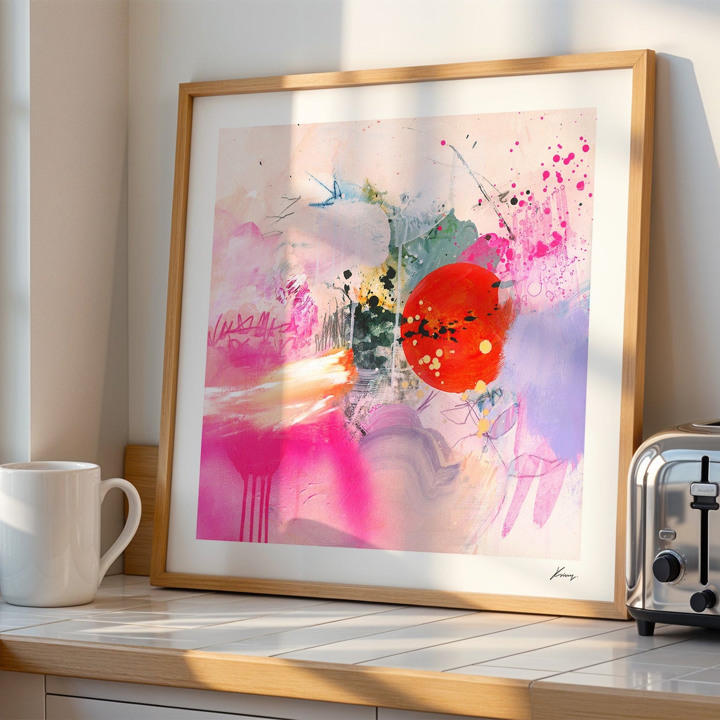 Framed abstract art print on a kitchen counter next to a toaster 