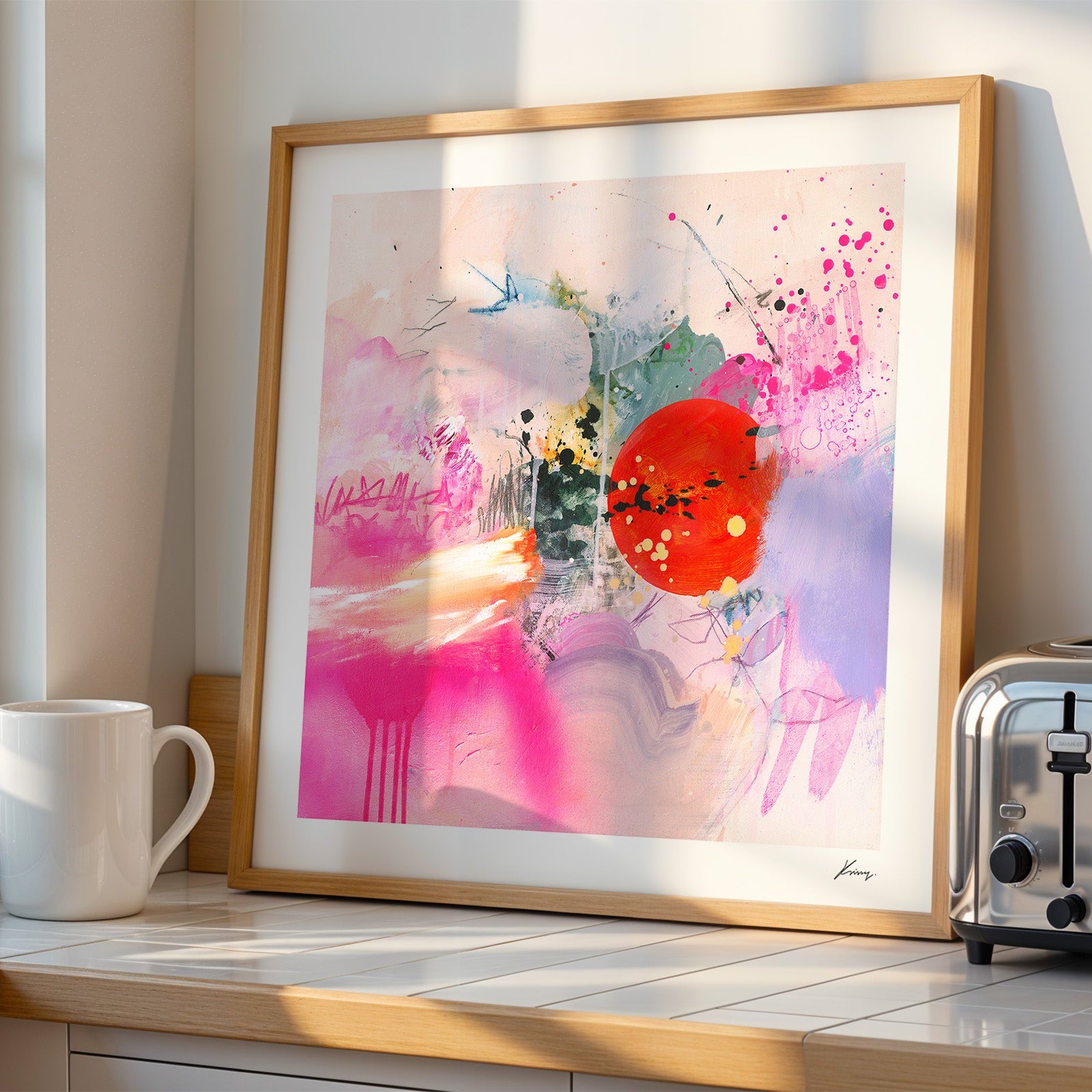 Framed abstract art print on a kitchen counter next to a toaster 