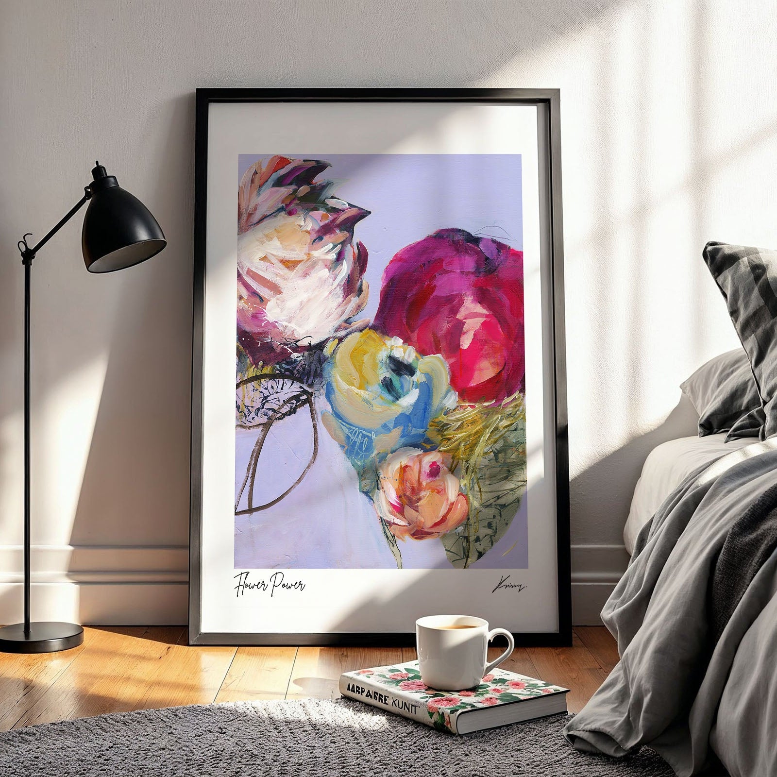 Framed abstract floral artwork in a living room setting with a lamp and coffee cup.