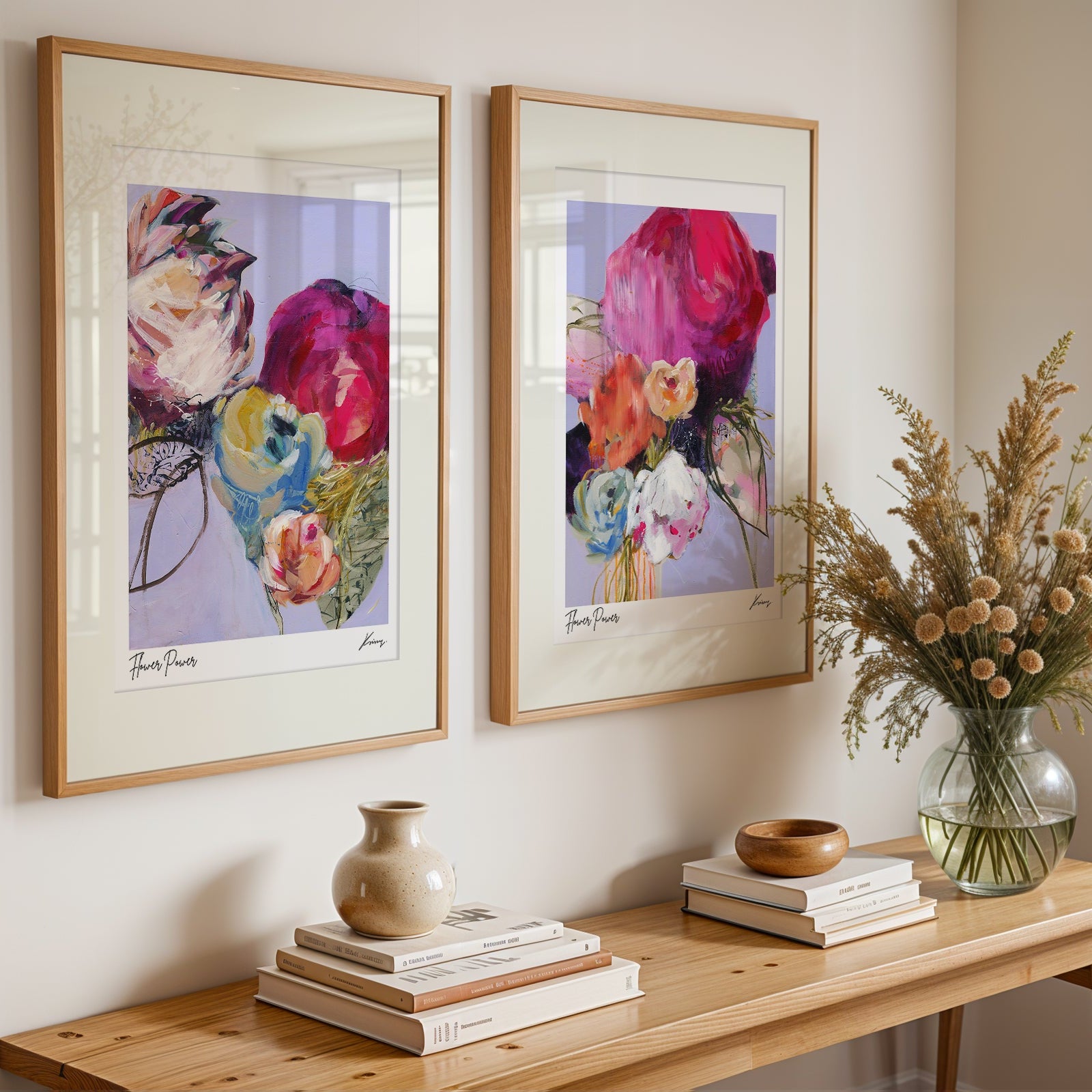 Two framed floral artworks on a wall above a wooden console table with decorative items.