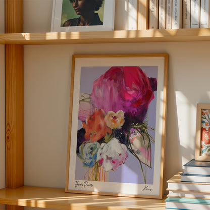 Framed artwork of flowers and a bird on a wooden shelf with books.