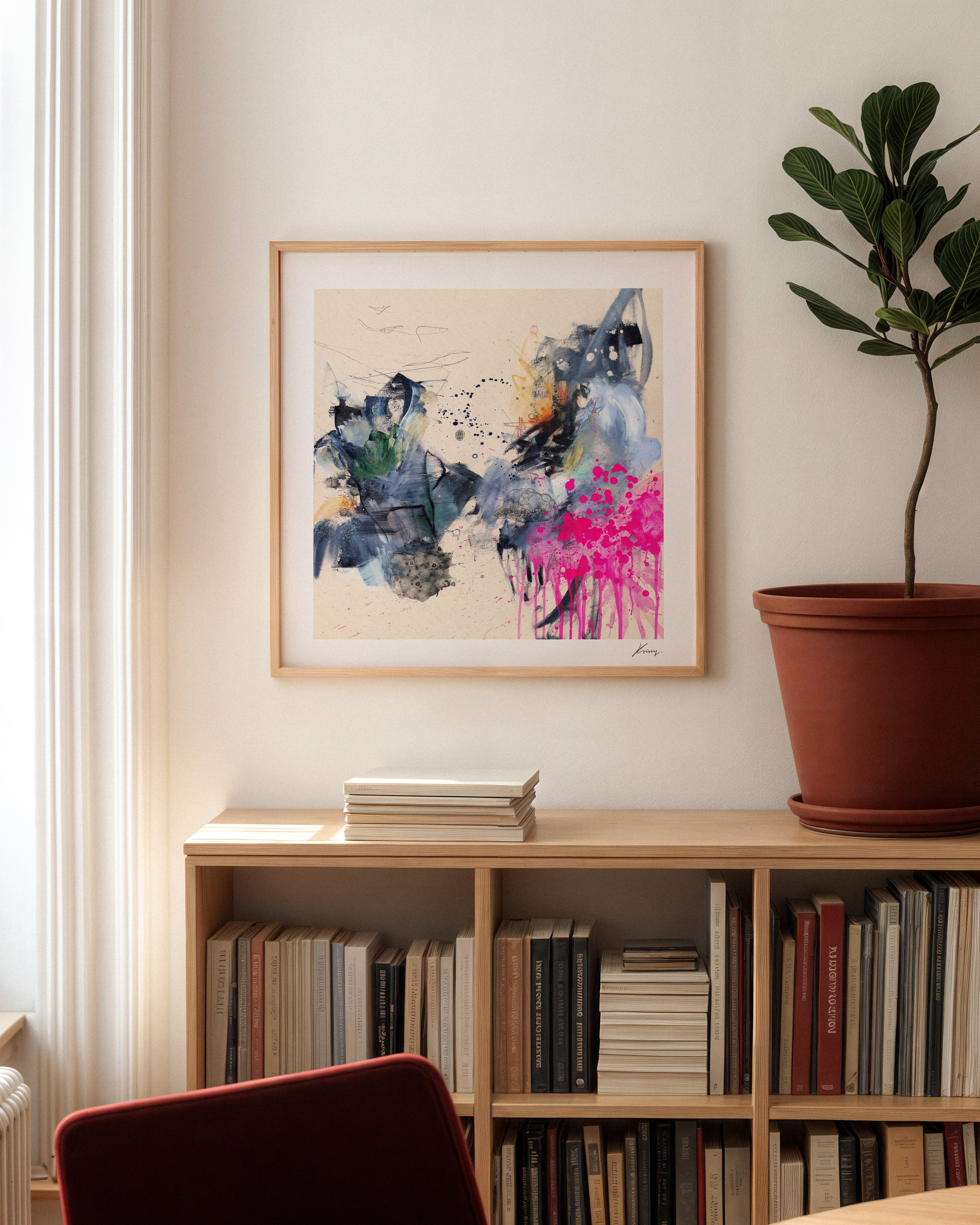 Framed abstract art above a bookshelf with books and a plant in a pot.