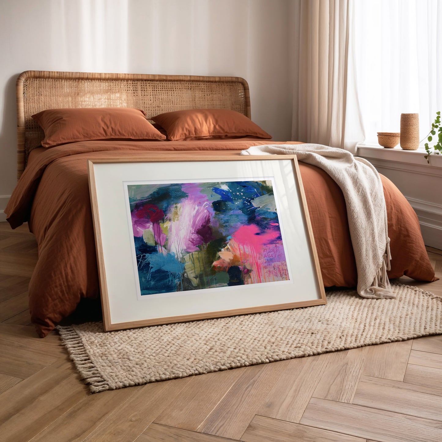 Framed abstract painting on a wooden floor in a bedroom setting