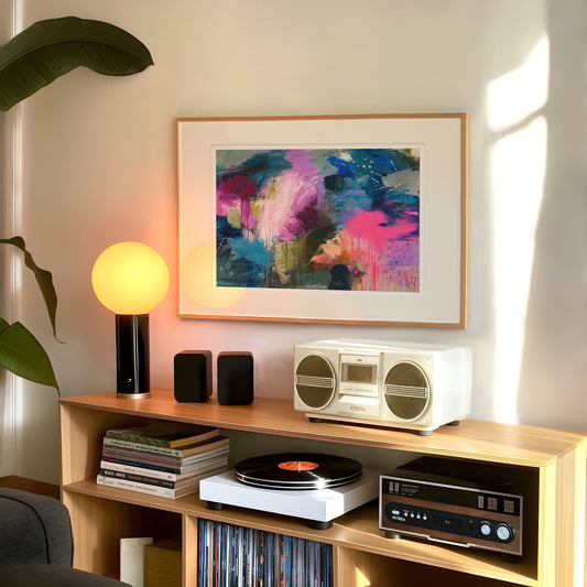 Wooden shelf with stereo equipment, books, and a colorful abstract painting on a wall.