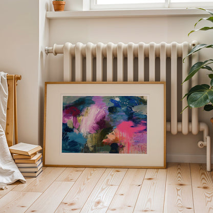 Framed abstract painting on a wooden floor with a radiator and plant in the background