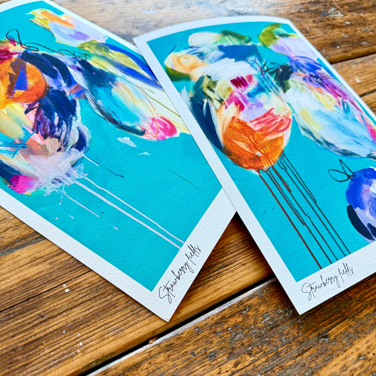 Two colorful greeting cards with artistic designs on a wooden surface