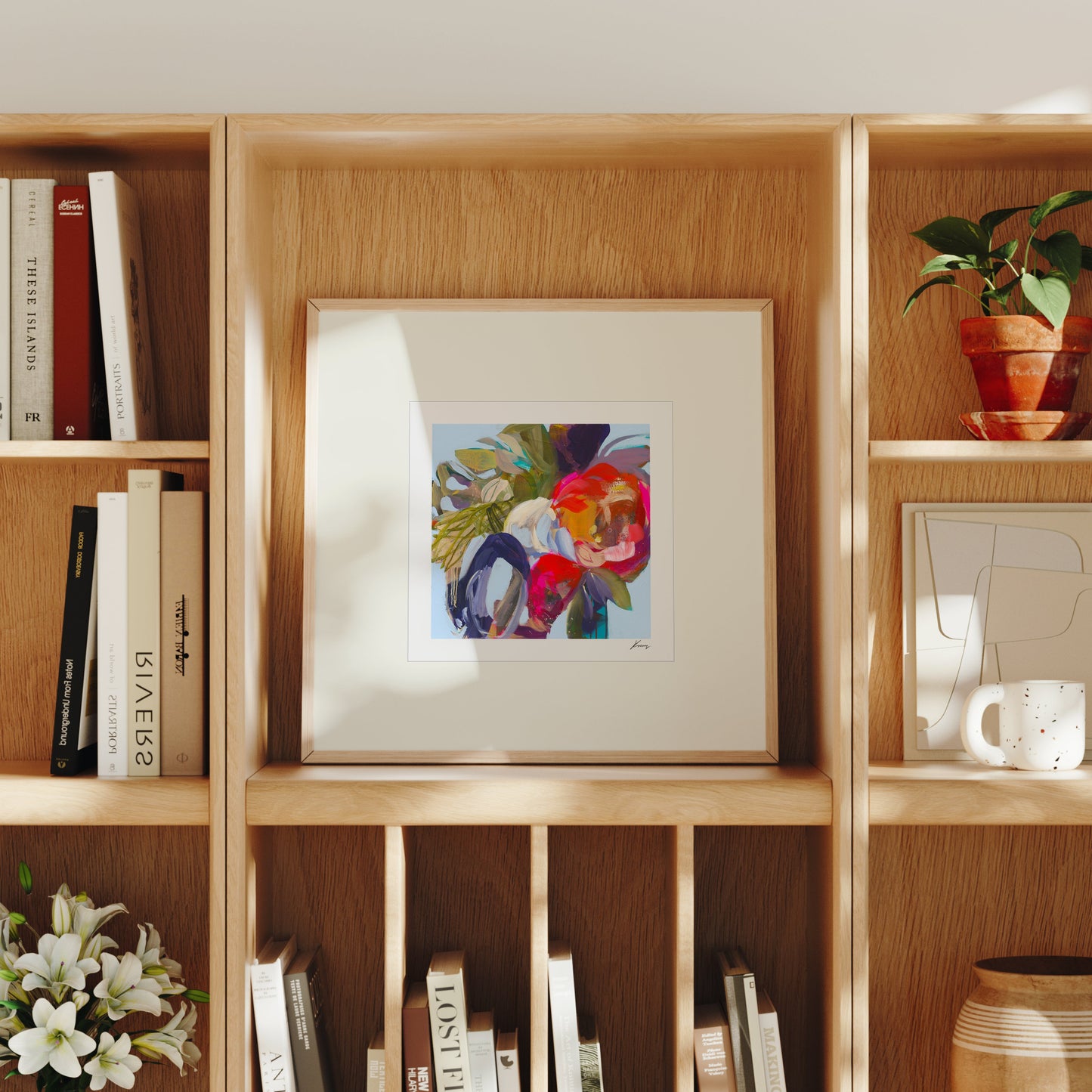 Wooden bookshelf with books, a framed abstract painting, and decorative items.