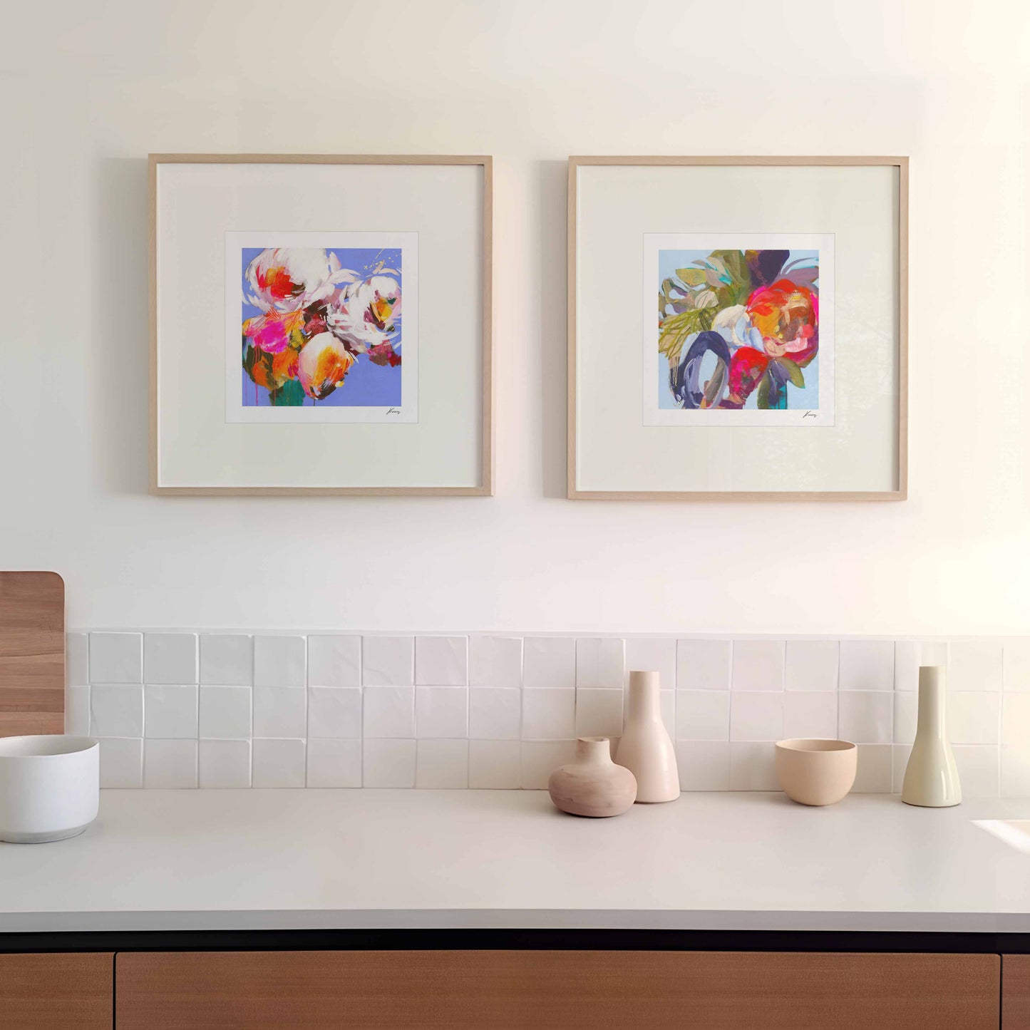 Modern kitchen with white countertops, wooden cabinets, and framed artwork on the wall.