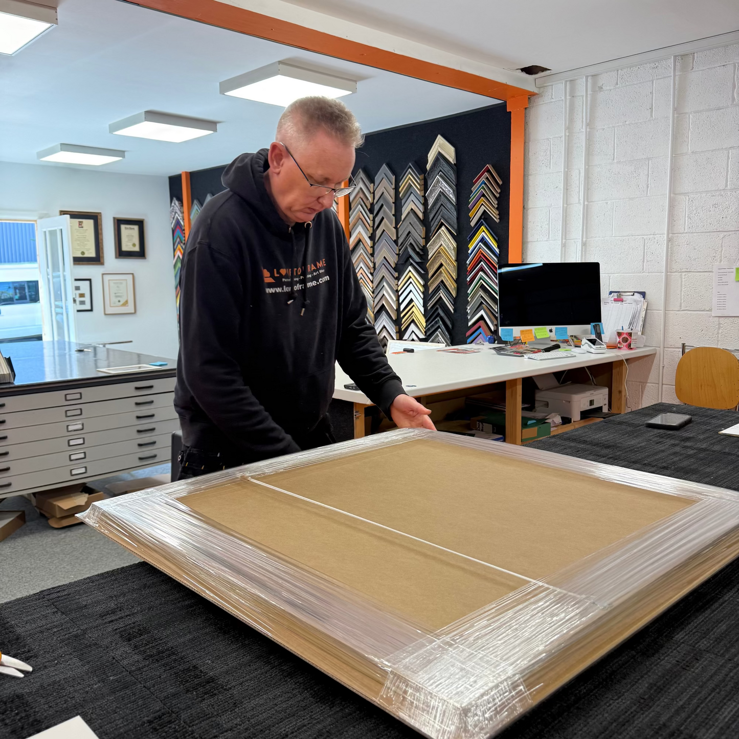 Man working with a large framed artwork in an art studio.