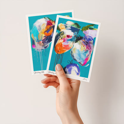 Two colorful abstract art cards held by a hand against a light background